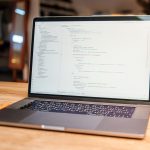A laptop displaying code in a bright, modern workspace