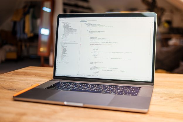 A laptop displaying code in a bright, modern workspace